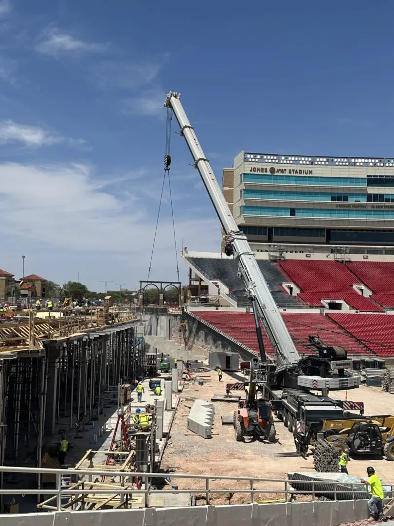 A crane is being used to lift the top of a football stadium.