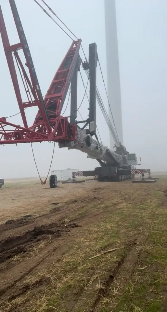 A large crane is in the middle of a field.