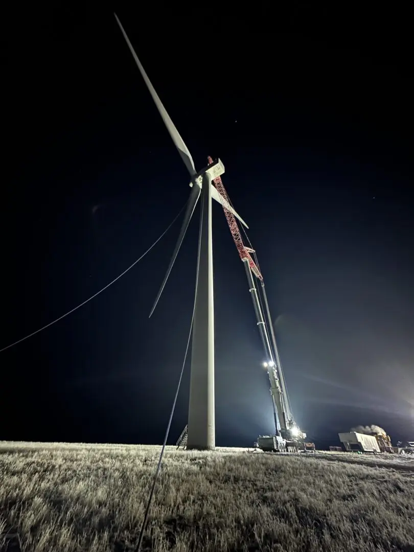 A crane is working on the top of a wind turbine.