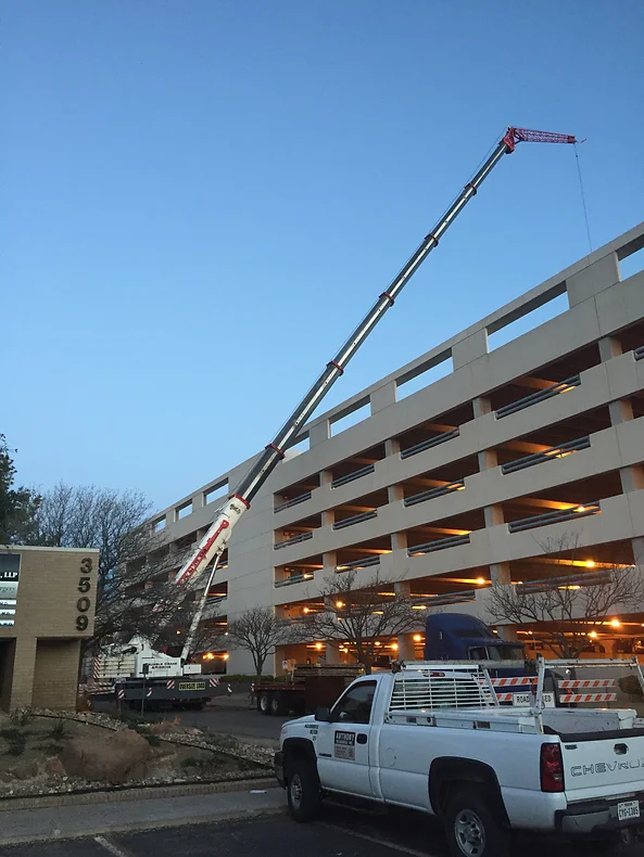 A crane is lifting up the roof of an apartment building.