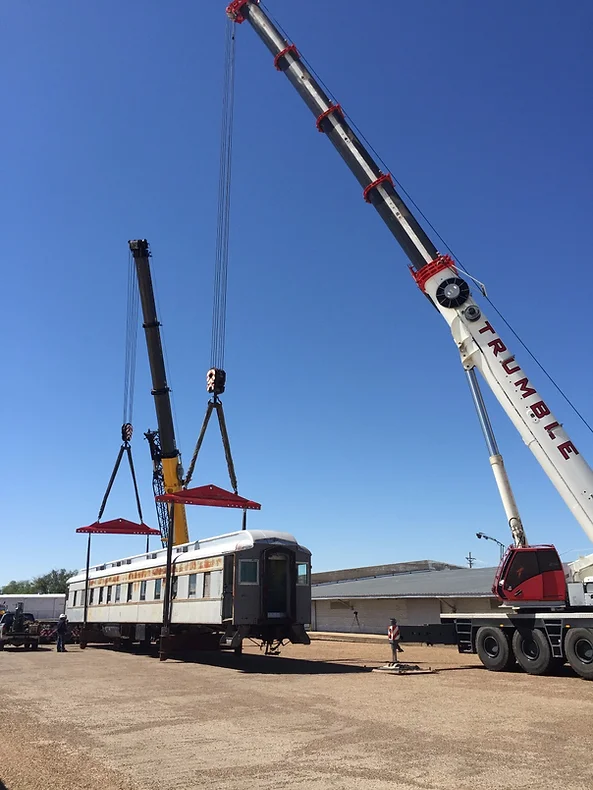 A crane is lifting a train car onto the ground.