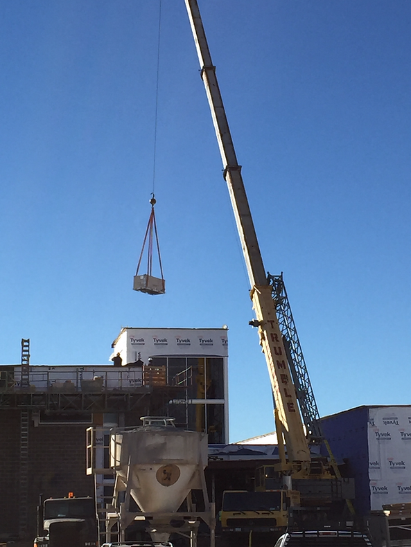 A crane is lifting a box on top of the building.