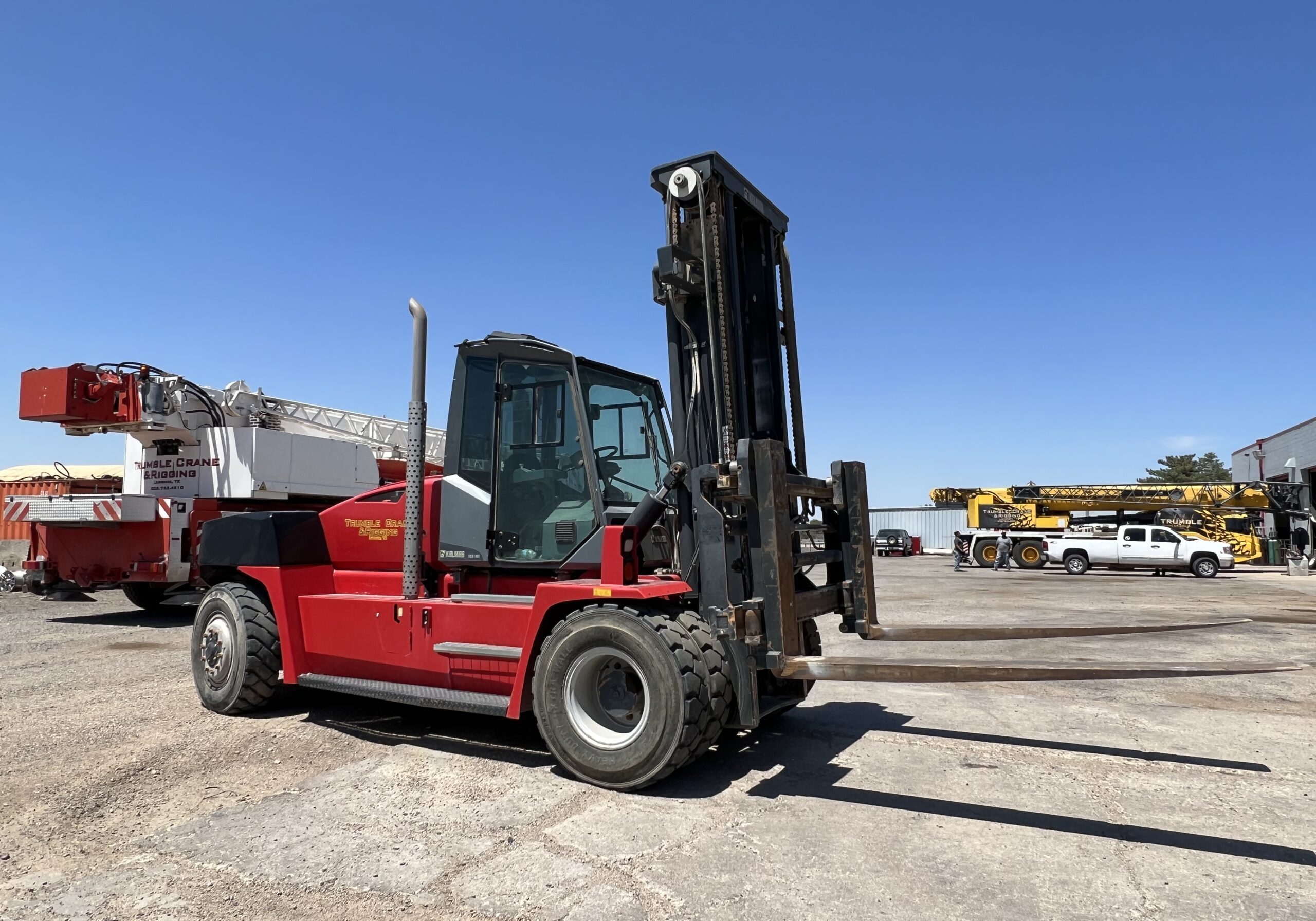 A large red forklift parked in an empty lot.