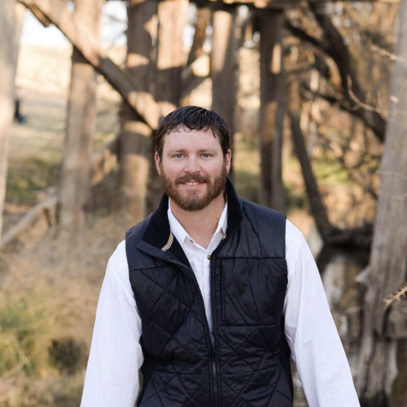 A man standing in front of some trees